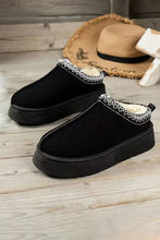 Lade das Bild in den Galerie-Viewer, Black slip-on Contrast Print Suede Plush Lined Snow Boots with thick soles and white plush interior lining, displayed on a wooden surface with a straw hat in the background.