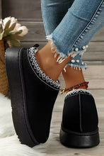 Lade das Bild in den Galerie-Viewer, Close-up of feet wearing black Contrast Print Suede Plush Lined Snow Boots with white stitching detail, paired with distressed blue jeans featuring pearl embellishments.
